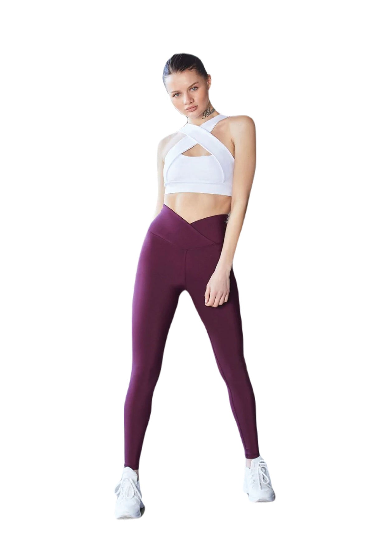 Person in einem weißen bauchfreien Top, Lisminas 1087 Ve Waist Leggings in Dunkelviolett und weißen Sneakers vor weißem Hintergrund.